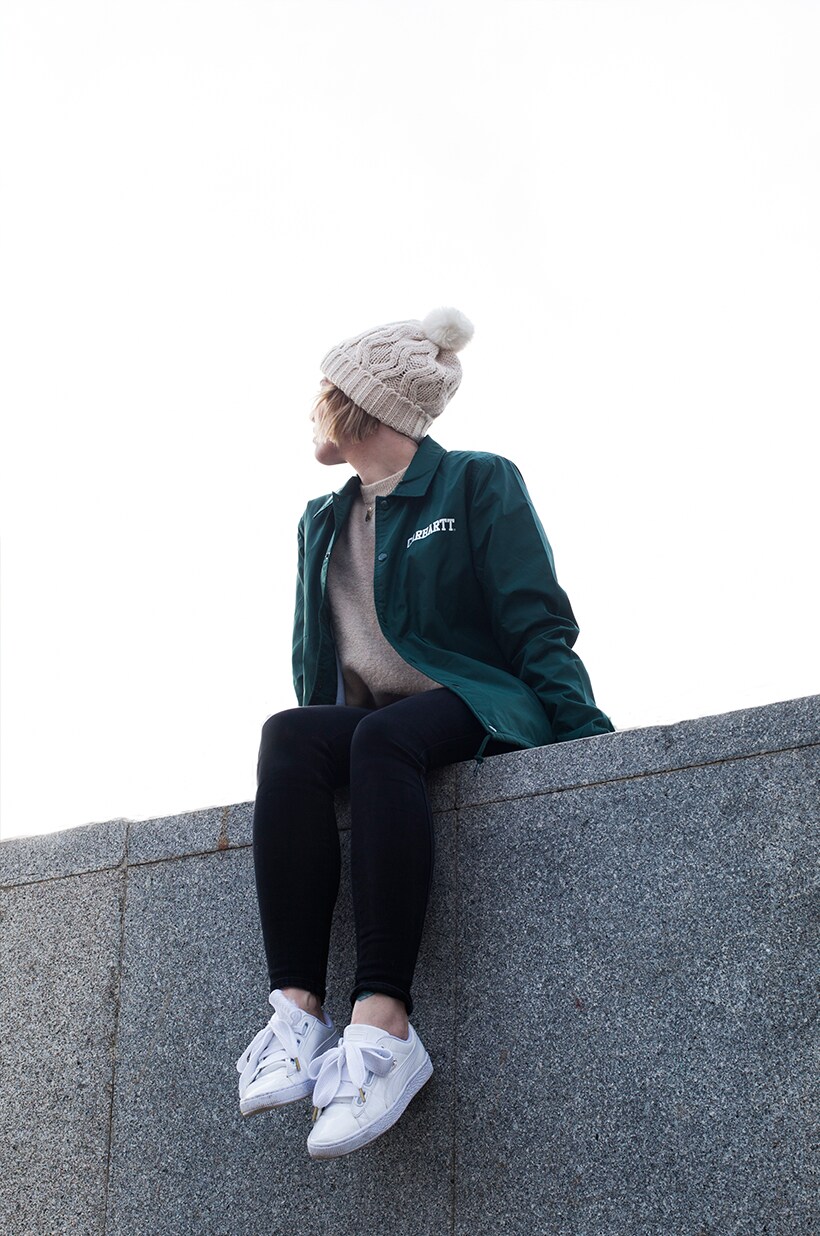 Matilda Anton sat on a wall wearing Carhartt coach jacket